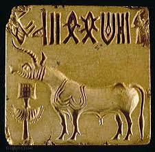 A carved stone seal from the Harappan Civilization depicting a mythical unicorn-like creature, with a single horn, detailed body, and a short tail. The creature is shown in profile, with its head turned slightly, and is surrounded by intricate geometric patterns.